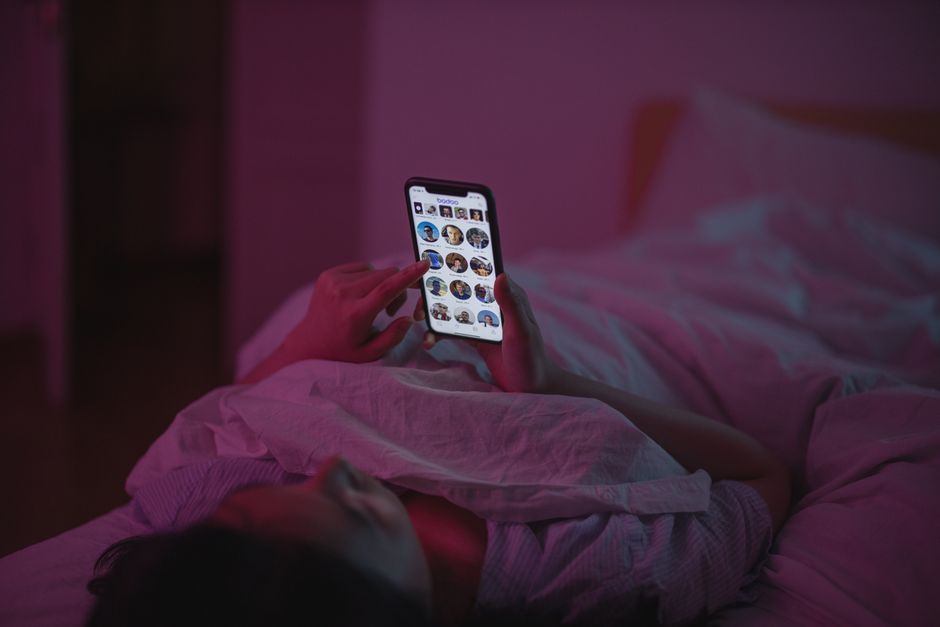 침대에서 수면 기기를 손에 쥐고 편안하게 누워 있는 사람